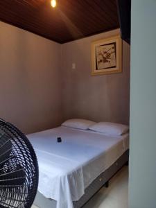 Habitación con cama con sábanas blancas y una foto en la pared. en Suíte Verano 1,2,3 e 4 en Niterói