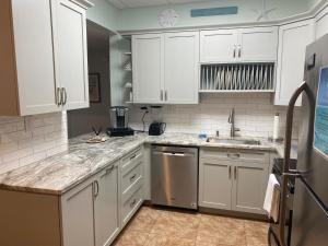 a kitchen with white cabinets and stainless steel appliances at Your Beach Therapy Awaits at Sans Souci in Pensacola Beach
