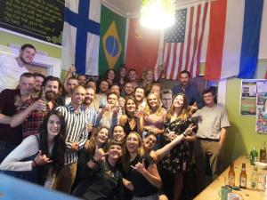 un gruppo di persone che posano per una foto in una stanza con le bandiere di Worldwide Backpackers a Wellington