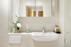 een witte badkamer met een wastafel en een spiegel bij Spitafields 2 Bed Shoreditch Apartment in Londen