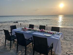 a dinner table on the beach with the ocean at Boli Villa Thoddoo in Thoddoo