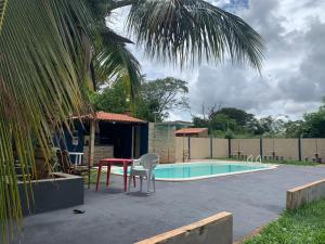 una piscina con mesa, sillas y una palmera en Hotel Pousada Lagoa Azul, en Paranaíba