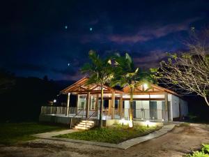 a house with a porch and palm trees at night at Pousada Rural Recanto do Lago in Pedra Azul