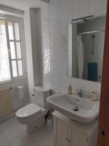 Baño blanco con aseo y lavamanos en PRECIOSA CASA DE 4 HABITACIONES EN PLENO CORAZÓN DEL CAMINO DE SANTIAGO!, en Palas de Rei 