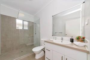 a white bathroom with a toilet and a sink at 4 bed 2 bath home in Idalia in Oonoonba