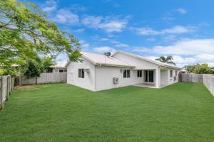 a white house with a fence and a yard at 4 bed 2 bath home in Idalia in Oonoonba