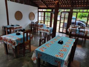 un restaurante con mesas y sillas en una habitación con ventanas en Pousada Colonial, en Pirenópolis