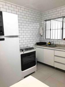 eine weiße Küche mit einem Herd und einem Kühlschrank in der Unterkunft Encontro Open House in São Paulo