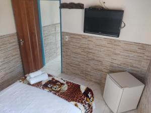 Habitación con cama y TV en la pared. en Pousada Colonial, en Pirenópolis