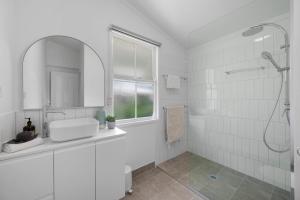 a white bathroom with a shower and a sink at Charming 3-Bedroom Retreat in Townsville