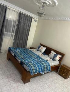 een slaapkamer met een bed met een blauw dekbed en een raam bij Appartement meublé F4 Maristes, Dakar in Dakar