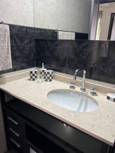 Un mostrador de baño con un lavabo y un espejo. en Cambacuá Santa Ana!, en Villa María