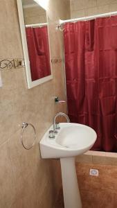 a bathroom with a sink and a red shower curtain at La Elvira in San Antonio de Areco