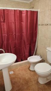 ein Badezimmer mit zwei WCs und einem roten Duschvorhang in der Unterkunft La Elvira in San Antonio de Areco