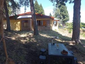 una mesa de picnic frente a una casa con árboles en Casa Arrayan - Entorno único 20 metros del lago en San Carlos de Bariloche