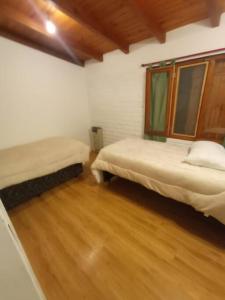 een kamer met 2 bedden en een houten vloer bij Casa Arrayan - Entorno único 20 metros del lago in Bariloche