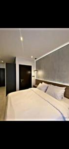 a bedroom with a large white bed with a gray headboard at The Signature Hotel Apartment Accra Ghana in Accra