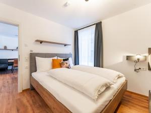 duże białe łóżko w pokoju z oknem w obiekcie Falken Suites TOP 2 w Kaprunie