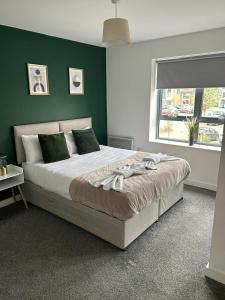 1 dormitorio con 1 cama grande y pared verde en Long Stay - Free Parking - Contractors - Train Station - Students, en Colchester