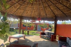 un patio con sombrilla de paja, sofá y mesa en Casa campestre familiar con alberca y areas recreativas, en Totolapan