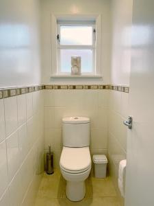 a white bathroom with a toilet and a window at Home in central Auckland in Auckland