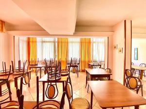 a restaurant with wooden tables and chairs and windows at Hotel Majorca Nuova Gestione Rimini 100 m dalla spiaggia in Rimini