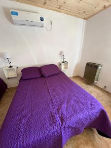 Cama morada en habitación con ventilador en Departamentos Avellaneda en Carhué