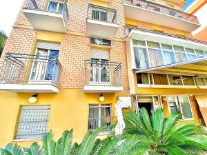 a yellow building with balconies and a palm tree at Hotel Majorca Nuova Gestione Rimini 100 m dalla spiaggia in Rimini