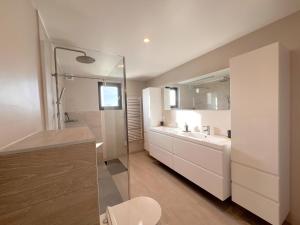 ein weißes Badezimmer mit einem Waschbecken und einem Spiegel in der Unterkunft De Golfbreker in Middelkerke