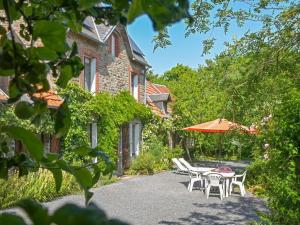 une terrasse avec une table, des chaises et un parasol dans l'établissement Gite Le Chevalier, à Gavray