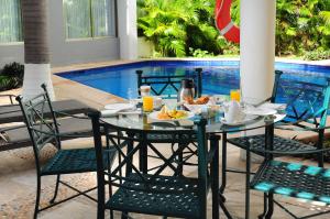 a table with a plate of food on it next to a pool at Ambiance Suites in Cancún