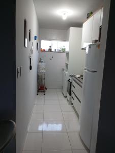 cocina con electrodomésticos blancos y suelo de baldosa blanca en Flat Sandra, en Teixeira de Freitas