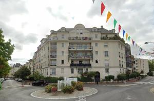 a large building on a street with flags on it at Charme & Confort au Plessis in Le Plessis-Robinson