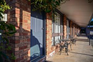 a brick building with a door and tables and chairs at Woomargama Motel in Woomargama