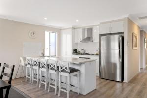 a kitchen with a stainless steel refrigerator and bar stools at Shoalhaven Escape Cowes in Cowes
