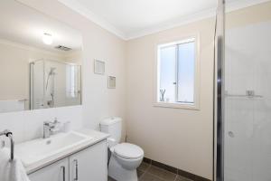 a white bathroom with a toilet and a sink at Shoalhaven Escape Cowes in Cowes +8 photos