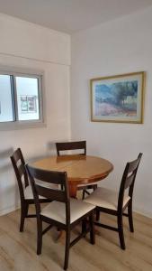einen Esstisch und Stühle mit einem Holztisch und einem Gemälde in der Unterkunft Hermoso departamento 4 personas in Buenos Aires
