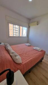 a bedroom with a bed with a red blanket and a window at Hermoso departamento 4 personas in Buenos Aires