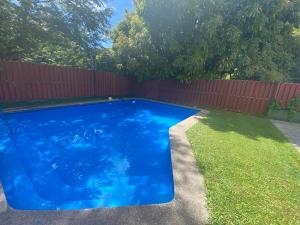 a blue swimming pool in a yard with a fence at Pucon departamento in Pucón
