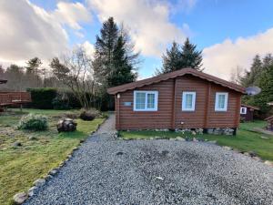 a small wooden cabin with a gravel driveway at Serene Snowdonia Retreat in Trawsfynydd