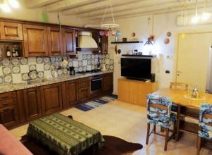 a kitchen with wooden cabinets and a table and a television at La casa dell'ulivo in Brembate