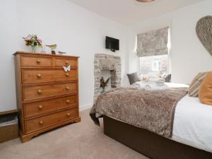 a bedroom with a large bed and a dresser at Gosling Cottage in Kendal