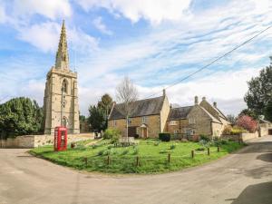 an old church with a red phone booth next to a street at Otter's View in Oakham