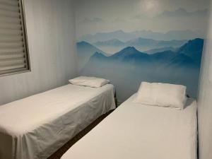 duas camas num quarto com montanhas ao fundo em Casa agradável em Santana próx. Expo Center Norte em São Paulo