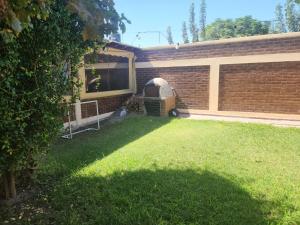 un patio trasero con una pared de ladrillo y una parrilla en San Felipe en Las Heras
