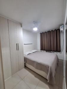 a white bedroom with a bed and a cabinet at Minha Praia Condomínios 2 in Rio de Janeiro