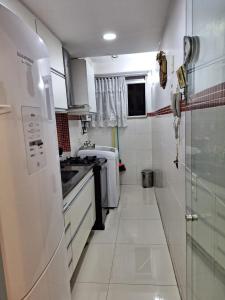 a white kitchen with a sink and a refrigerator at Minha Praia Condomínios 2 in Rio de Janeiro
