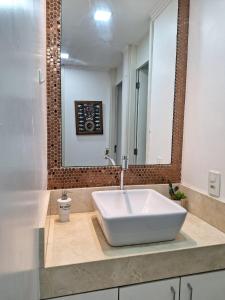a bathroom with a large white sink and a mirror at Minha Praia Condomínios 2 in Rio de Janeiro