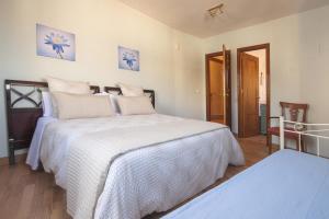 1 dormitorio con 2 camas con edredones blancos en Atico-Terraza Imperial, en Toledo