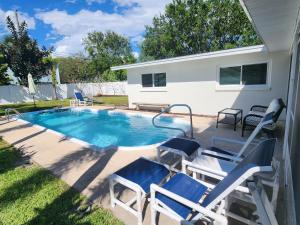 una piscina en el patio trasero con sillas y una piscina en Drift House - 4Bed 3Bath Private Pool House, en Cabo Cañaveral